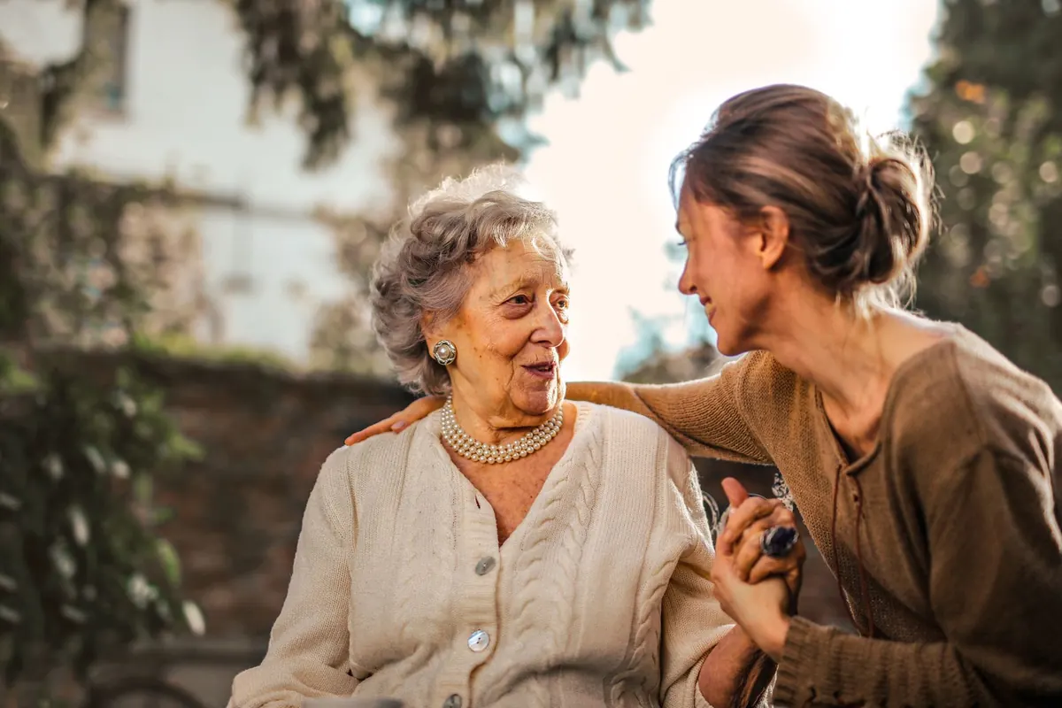 A smiling older lady and her carer sharing a happy moment in the garden